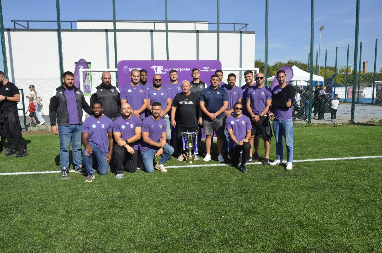 Jucătorii echipei de rugby SCM Timișoara cu un trofeu pe gazon