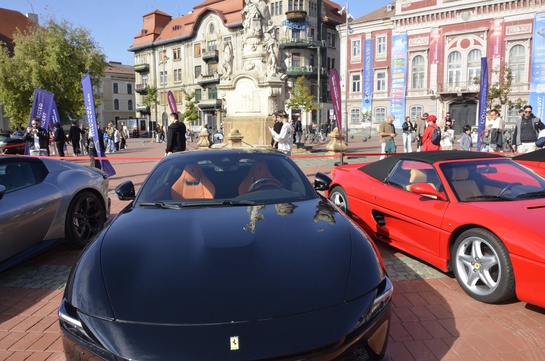 Ferrari negru și Ferrari roșu decapotabil, în fața vizitatorilor