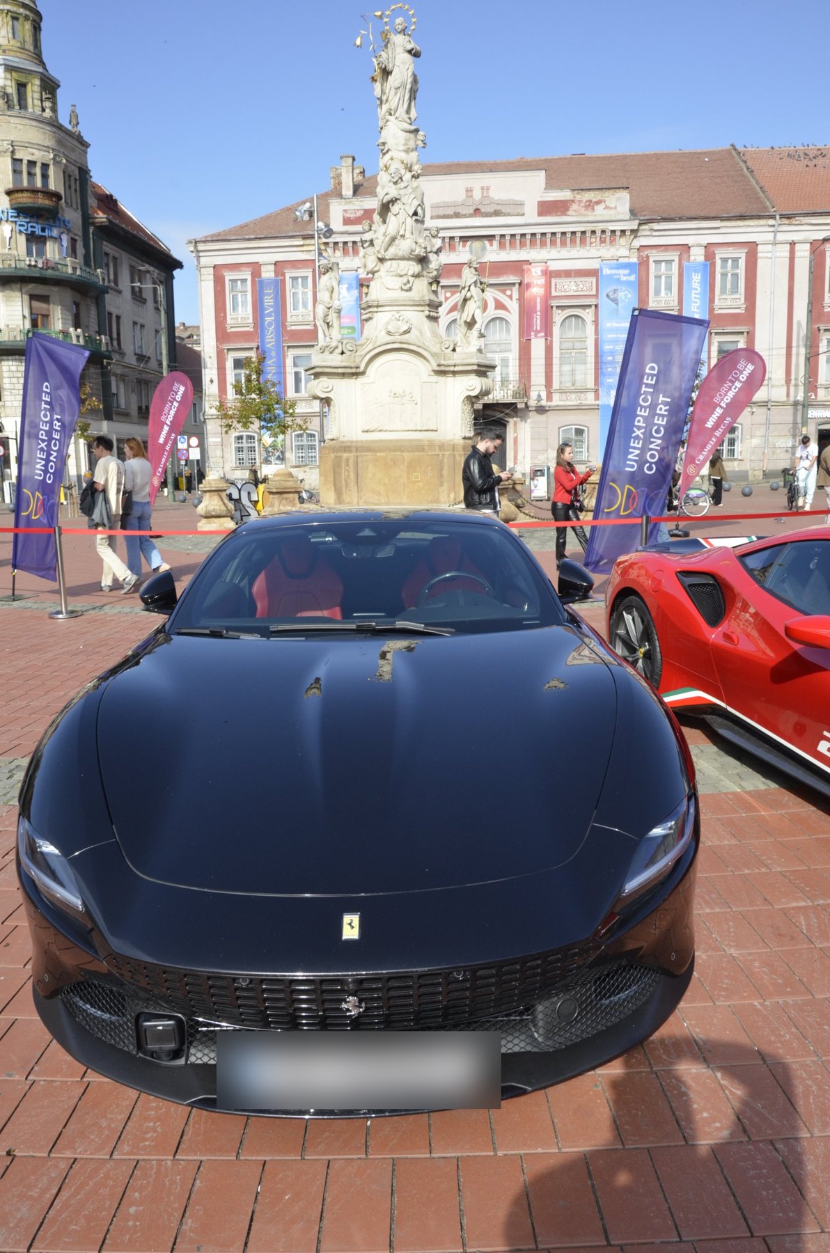 Ferrari negru, văzut din față (placa de înmatriculare blurată)