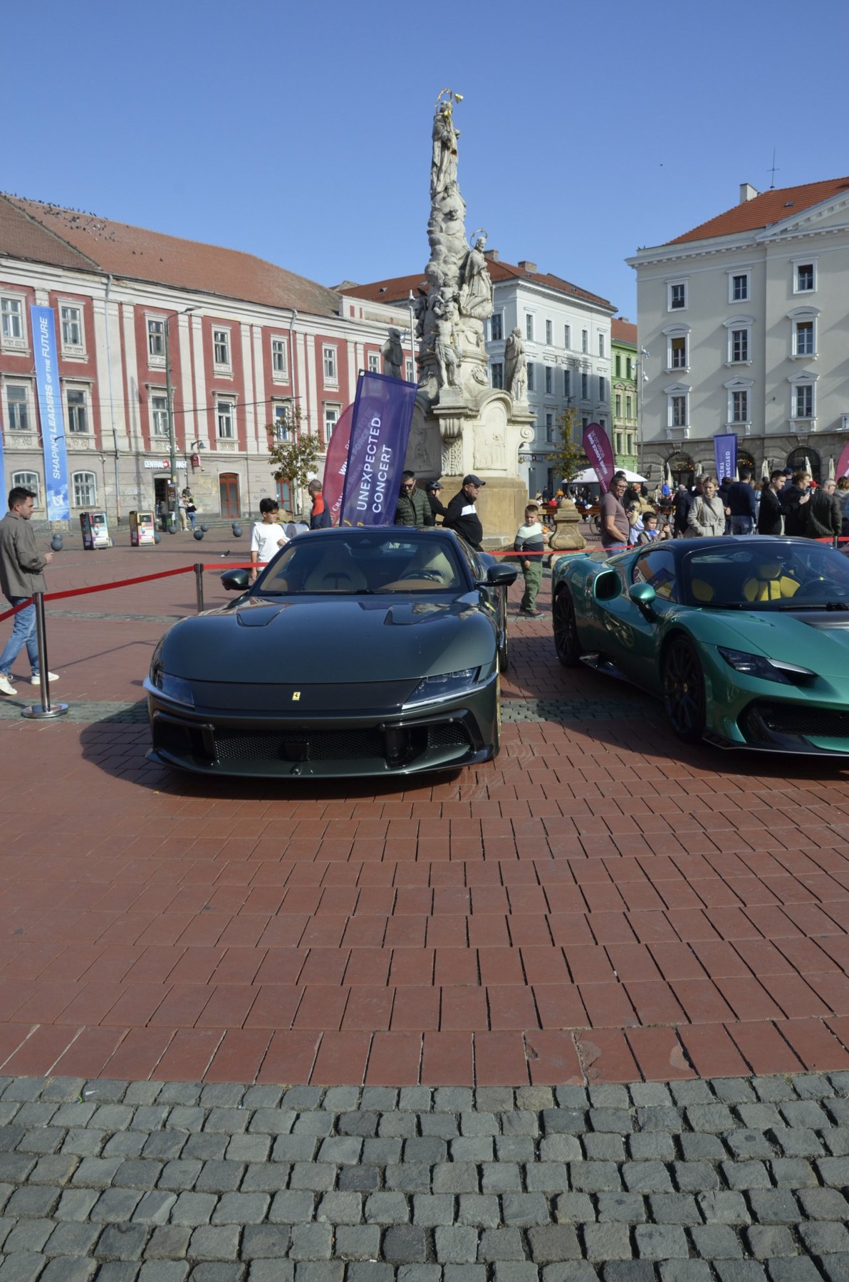 Ferrari gri-verzui și Ferrari verde, expuse lângă banda roșie