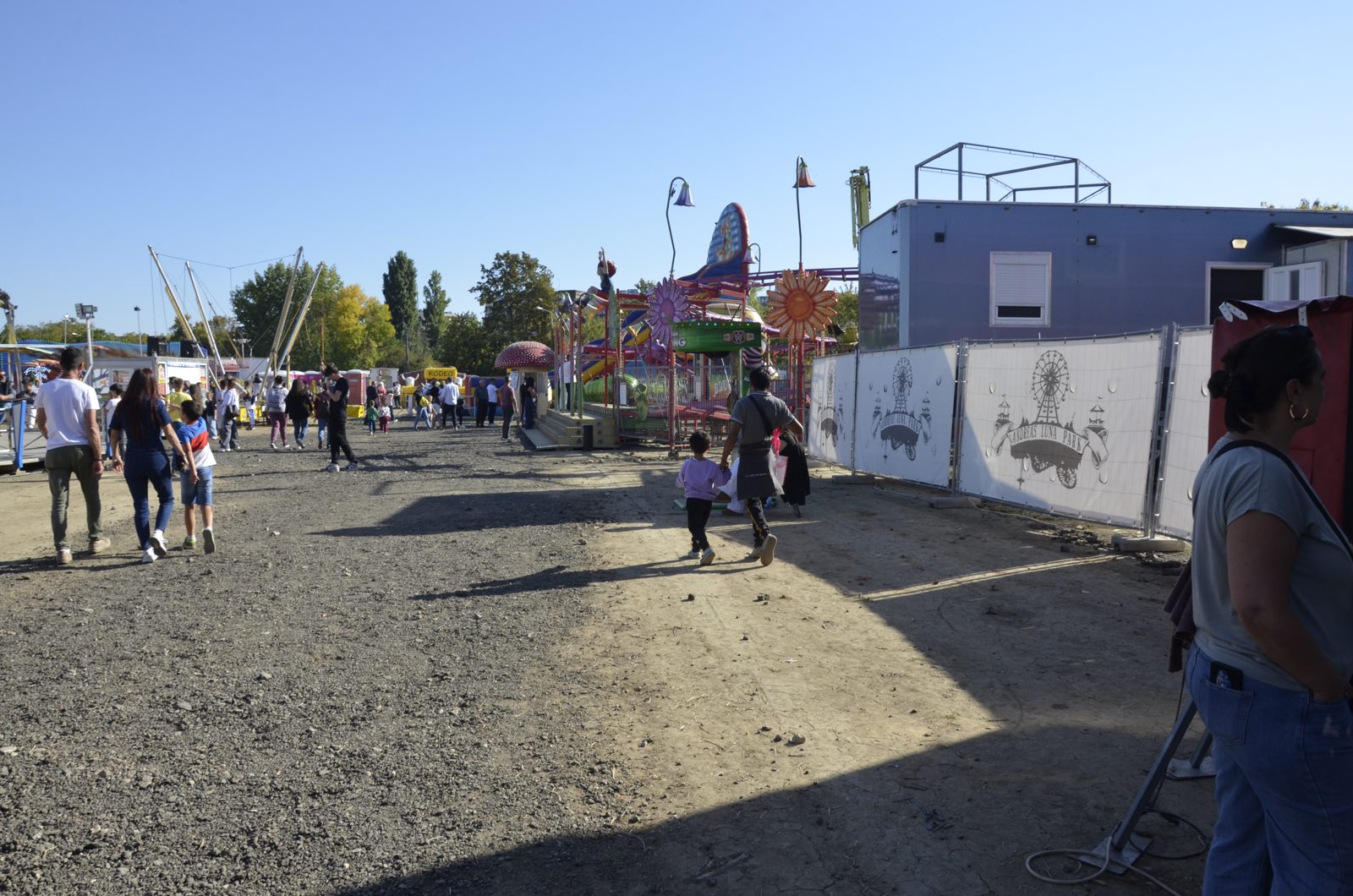 Aleea principală din lunapark, pe pietriș și pământ, cu public