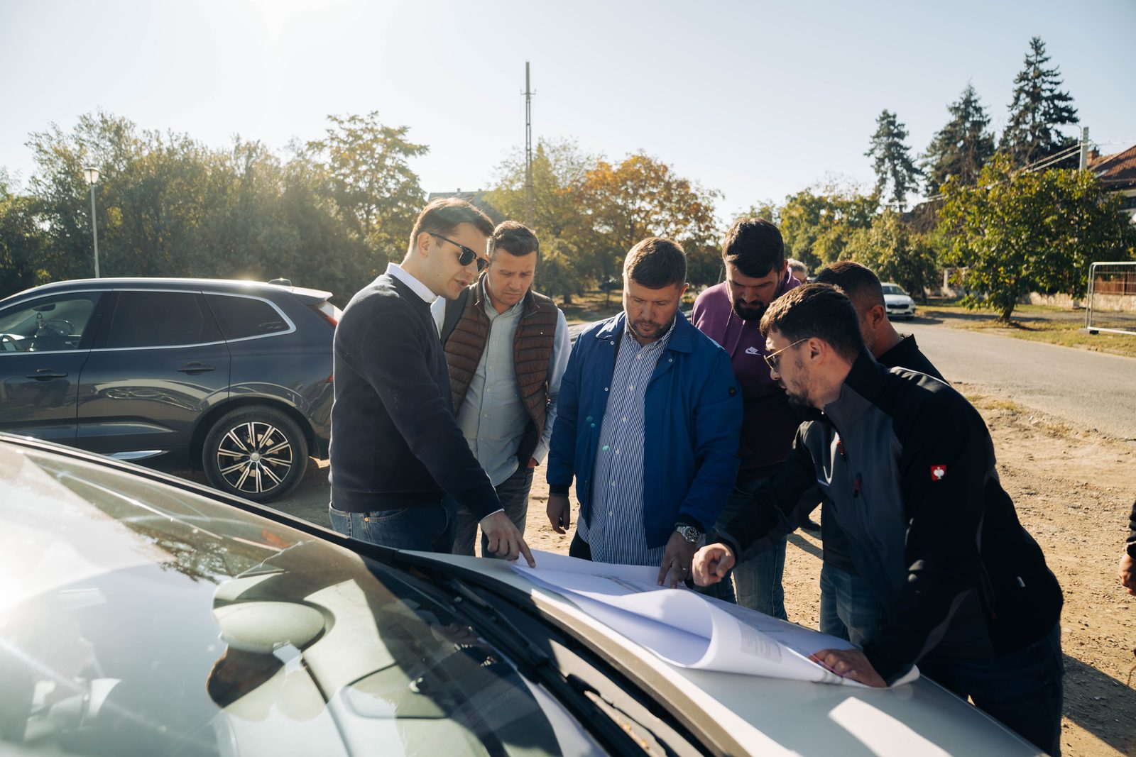 Reprezentanti ai Primariei si ai constructorului analizeaza planurile Podului Solventul pe capota unei masini
