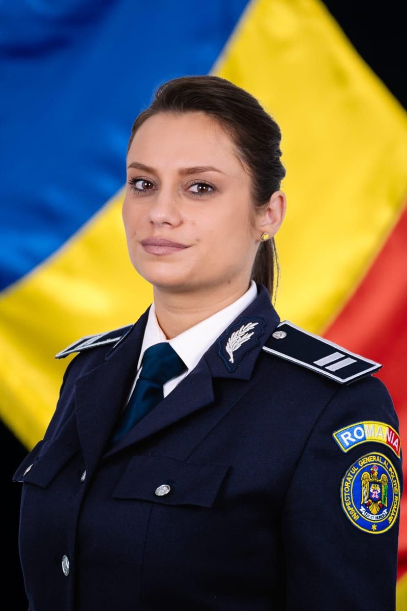 Polițistă în uniformă, în fața drapelului României