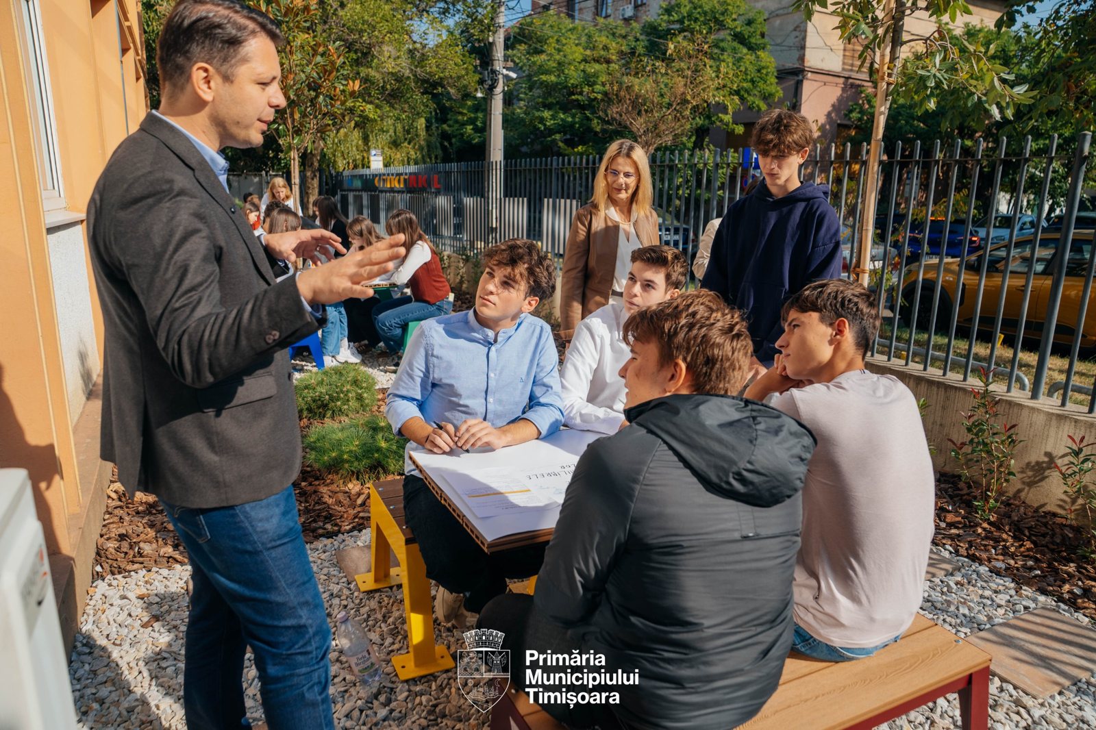 Discuție cu un grup de elevi la o masă cu bănci galbene