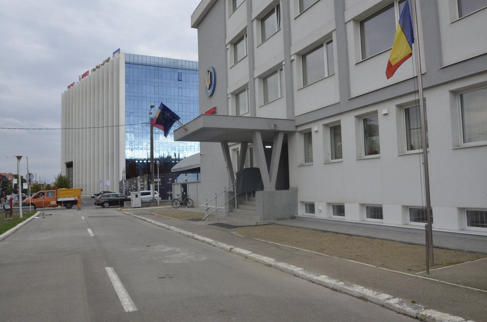 Fațada laterală a sediului IPJ Timiș, cu intrarea și o clădire de birouri din sticlă în fundal
