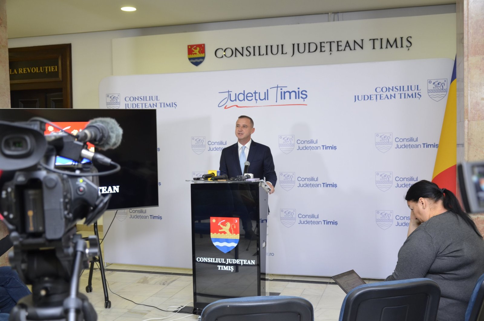 Alfred Simonis la pupitru, cu camera de filmat în prim-plan