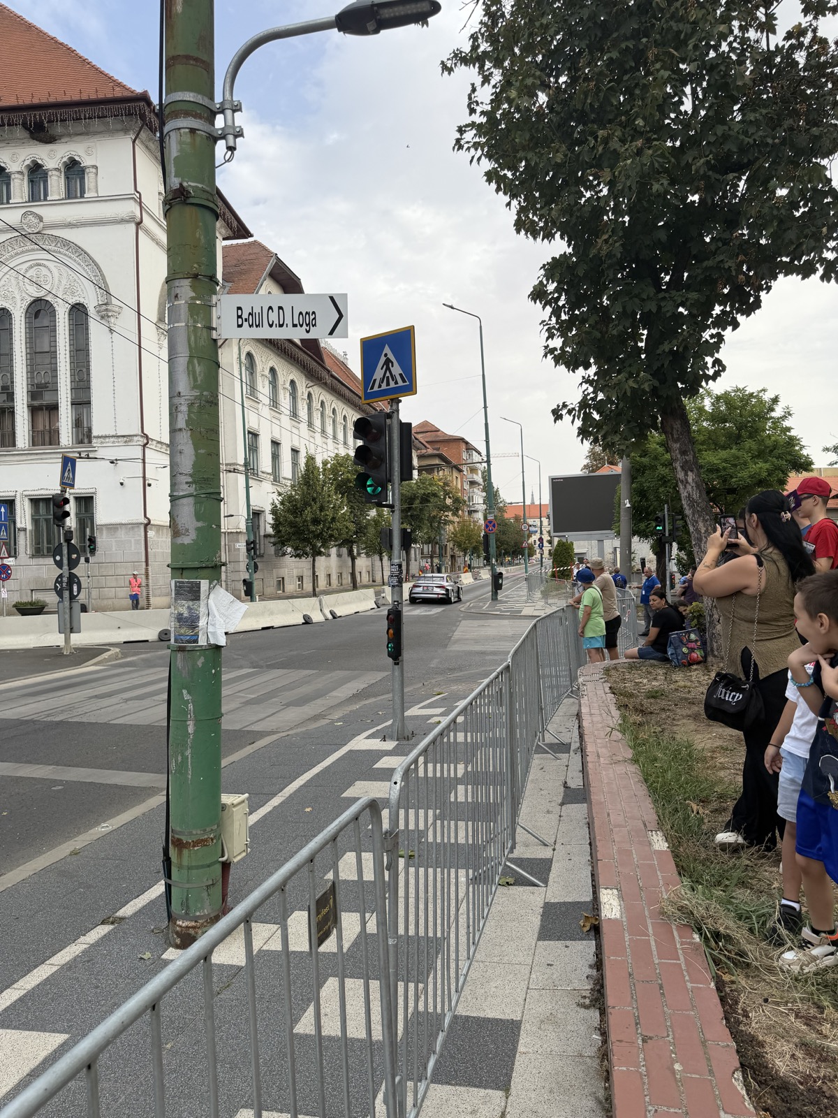 Mașină de curse trecând prin fața Primăriei Timișoara, cu semaforul pe verde în prim-plan