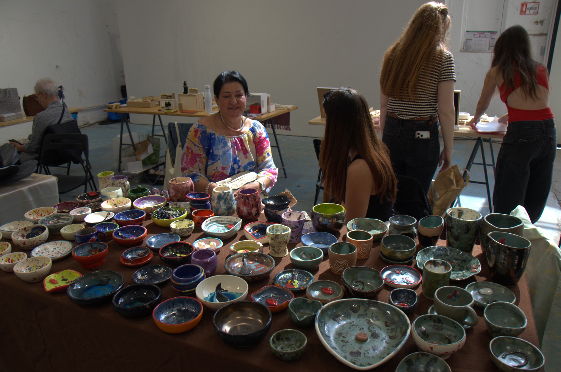 Artizană arătând o piesă de ceramică unei cliente