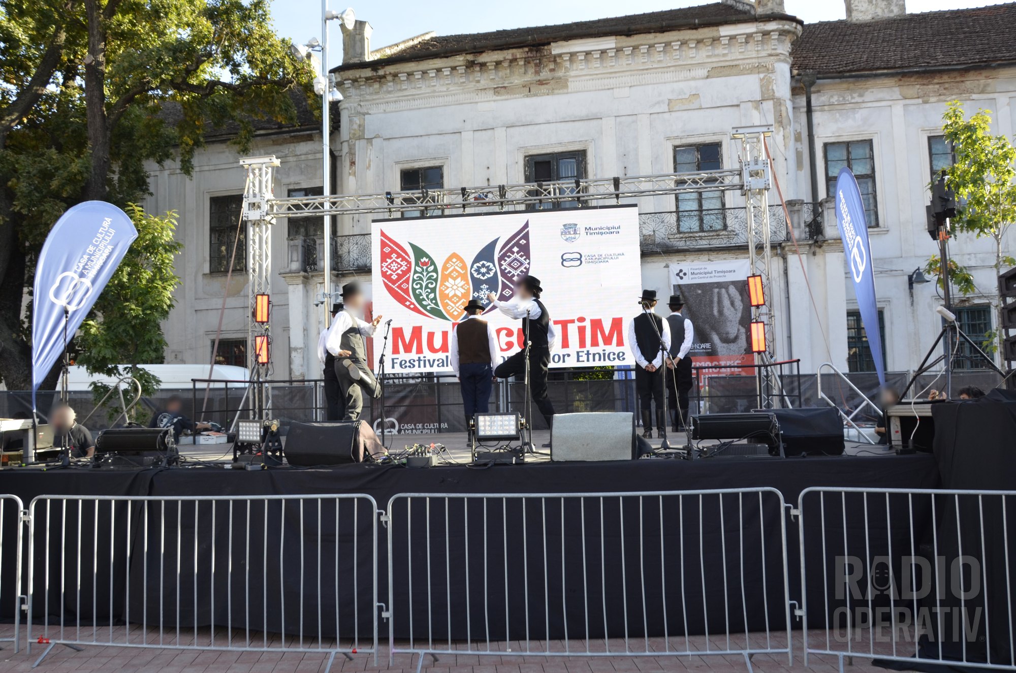 Scena MulticulTiM: dansatori în pălării negre și veste, în fața ecranului cu sigla festivalului