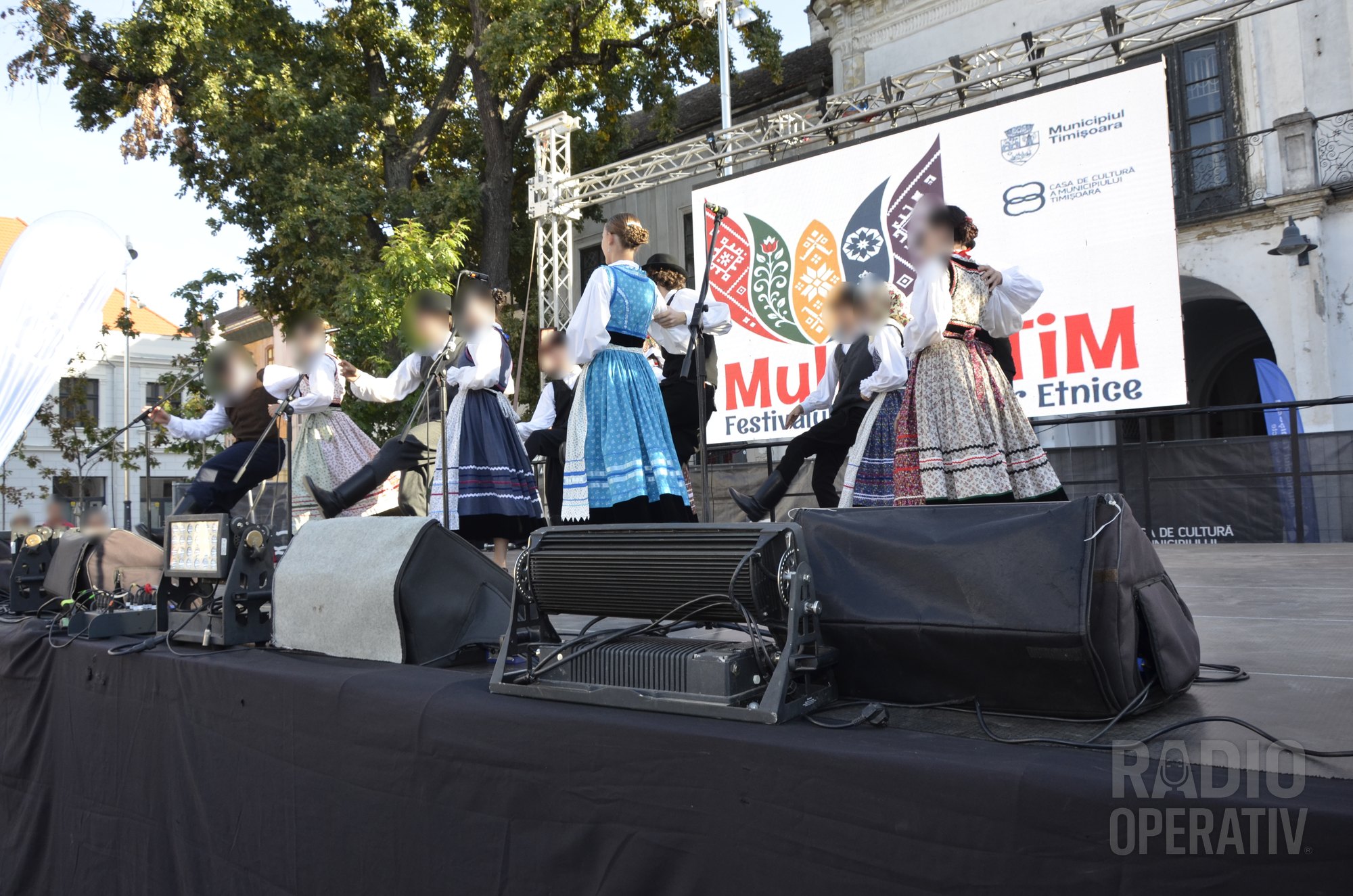 Perechi de dansatori în costume tradiționale, cu fuste largi și șorțuri albe
